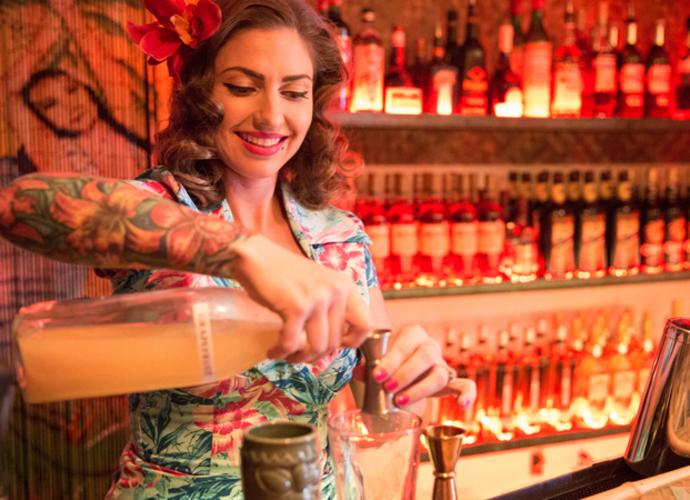 Bootlegger Tiki bar in Palm Springs full inside view woman bartender mixing drings.
